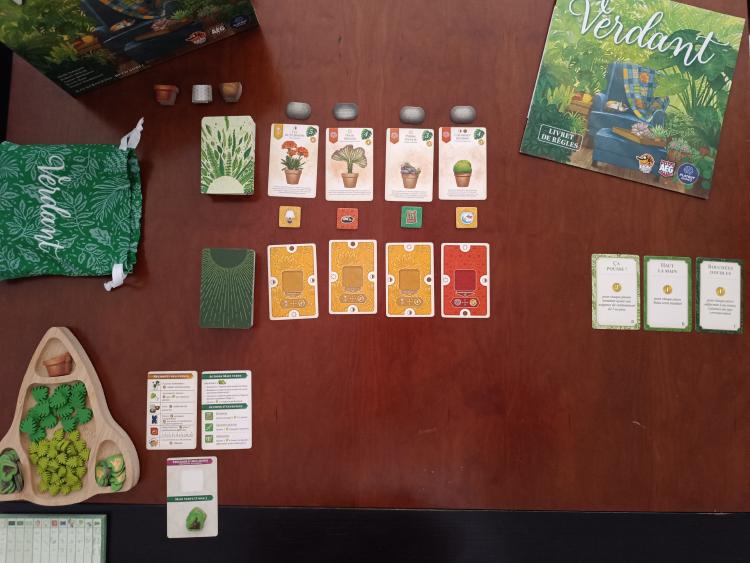 Verdant game setup with the rulebook, cloth bag, market cards and tokens, and wooden pot tray laid out on the table