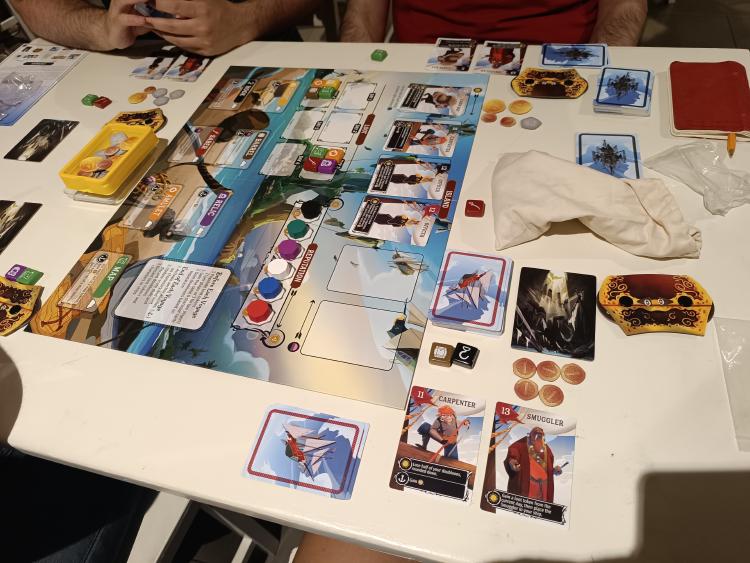 Libertalia: Winds of Galecrest board set up with crew cards, dice, coins and loot tokens on the table