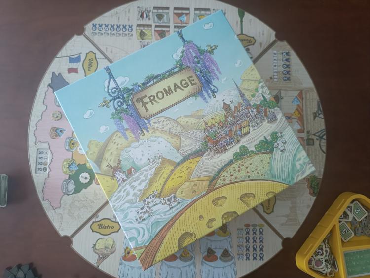 Fromage board game box lying diagonally on top of the assembled circular game board