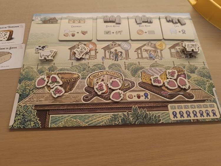 Close-up of a Fromage player board with structure tiles, cow and livestock tokens, and fruit and jam tokens arranged on the cheese boards