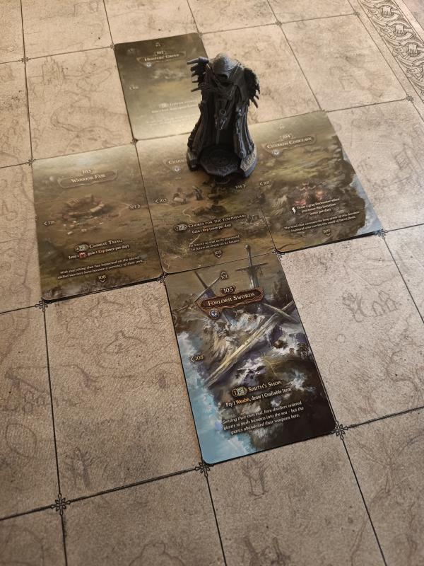 A menhir miniature standing on the Tainted Grail map, with the location cards spread around it